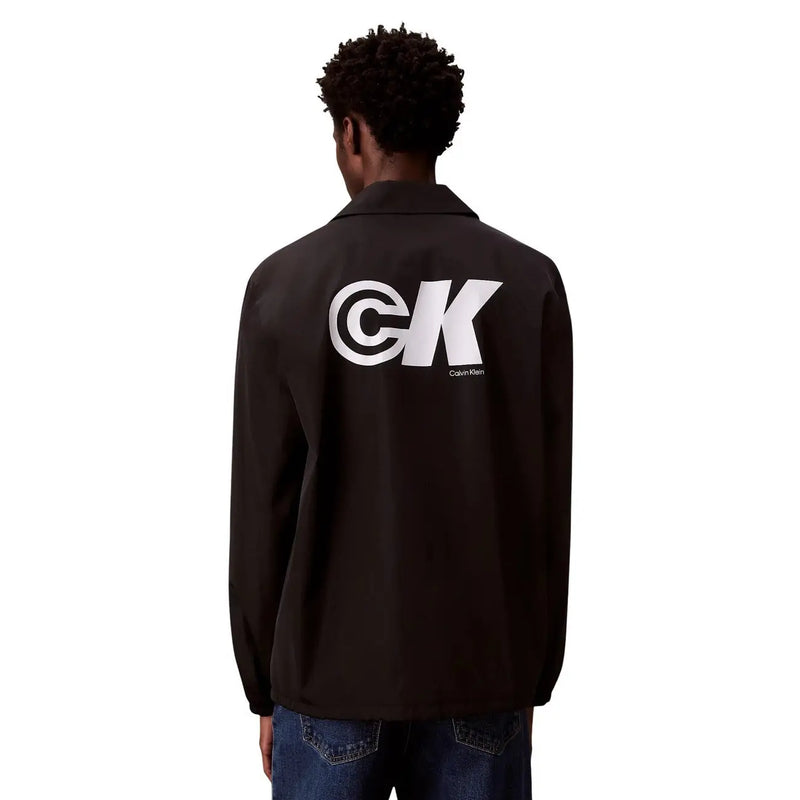 Rückansicht einer schwarzen Calvin Klein Coach-Jacke mit markantem weißen CK-Logo im klassischen Polyester-Blazer-Stil