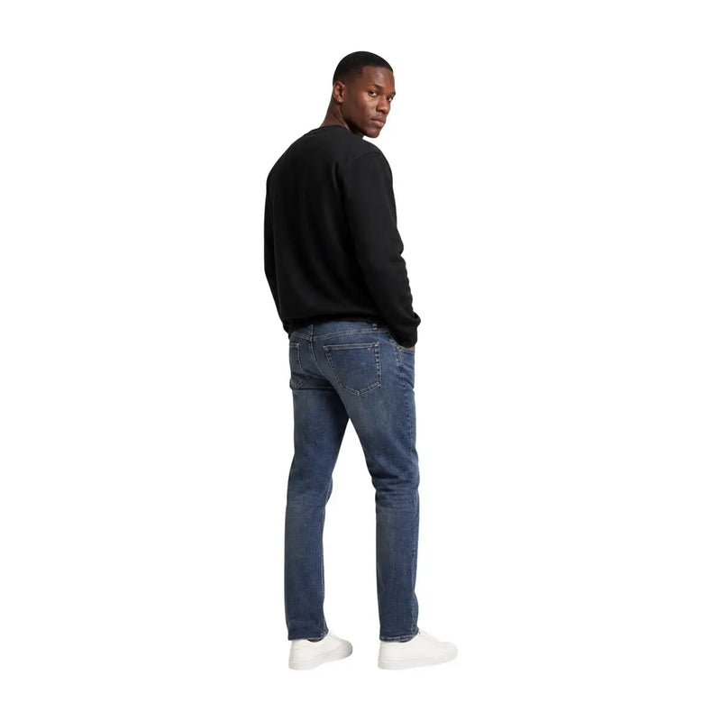 Dunkelblaue Jeans mit klassischem Five-Pocket-Design und dezenter Auswaschung an den Oberschenkeln, kombiniert mit einem schwarzen Baumwoll-Sweatshirt von Calvin Klein für Herren.