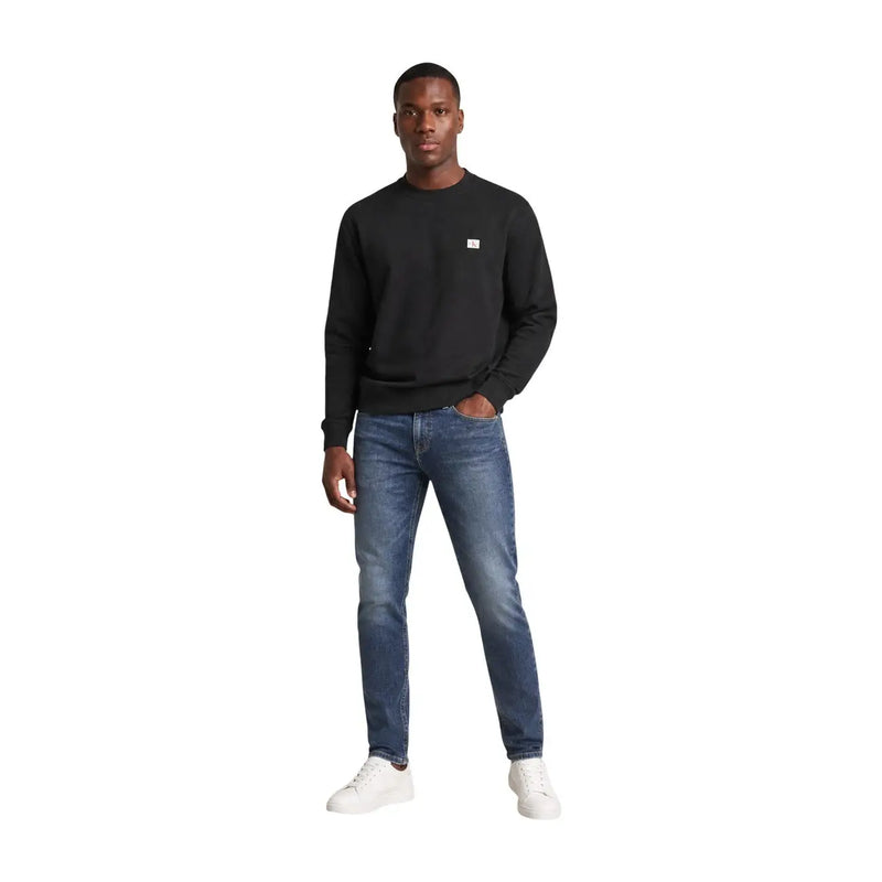 Calvin Klein Jeans Schwarzes Herren-Sweatshirt aus Baumwolle mit langen Ärmeln und Rundhalsausschnitt sowie einem kleinen weißen Logo auf der linken Brust.