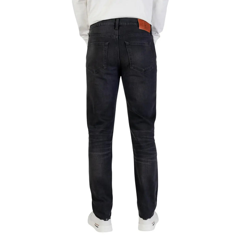 Dark-wash slim fit Calvin Klein cotton jeans for men with black zip button and brown leather brand patch at waistband