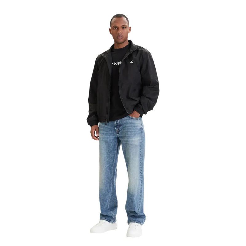 Black Calvin Klein jacket with subtle logos on chest and sleeve worn over matching black t-shirt with blue 100 cotton jeans