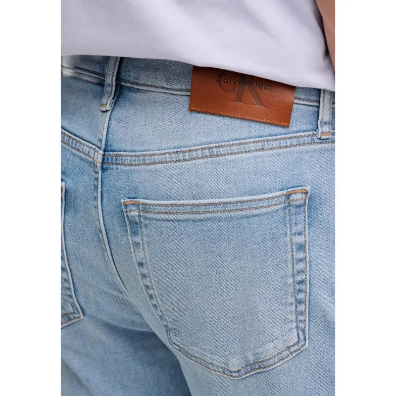 Rückansicht einer Calvin Klein Herren-Jeans aus blauem Baumwoll-Denim mit heller Waschung und braunem Leder-Markenpatch am Bund