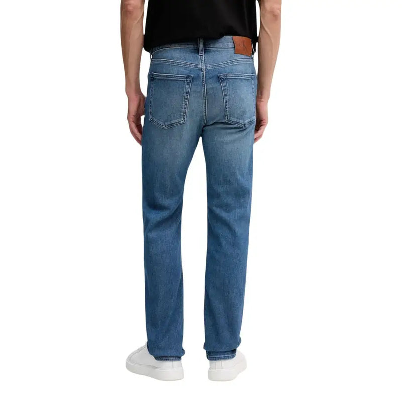 Rückansicht einer Calvin Klein Herrenjeans aus blauem Baumwoll-Denim mit geradem Bein und braunem Leder-Markenpatch.