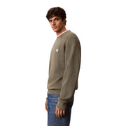 Calvin Klein Jeans Grüner Herrenpullover aus Baumwolle mit Waffelstrick, olivgrüner Struktur und kleinem weißen Logo-Patch auf der Brust