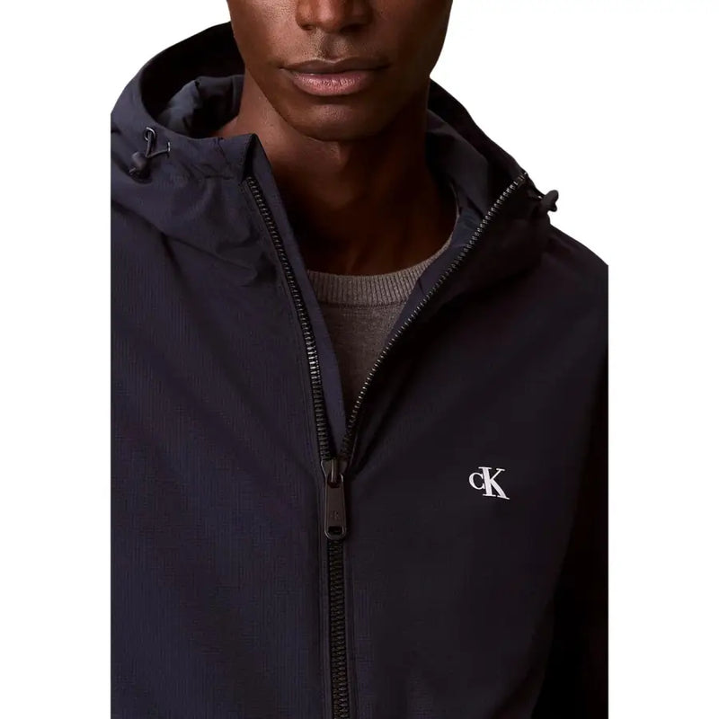 Calvin Klein Jeans Herrenblazer aus marineblauem Polyester mit Kapuze, dezenter Struktur und weißem, gesticktem Logo auf der linken Brust.