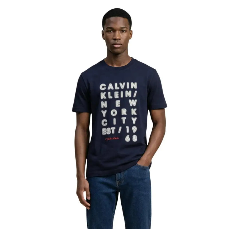 Marineblau Calvin Klein Jeans Männer t-shirt mit einer fetten weißen vertikalen Textgrafik und rotem Markennamen auf der Vorderseite