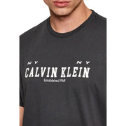 Dunkelgrau Calvin Klein Jeans Männer t-shirt mit einem markanten weißen Logo und dem Aufdruck „NY NY established 1968“ auf der Vorderseite