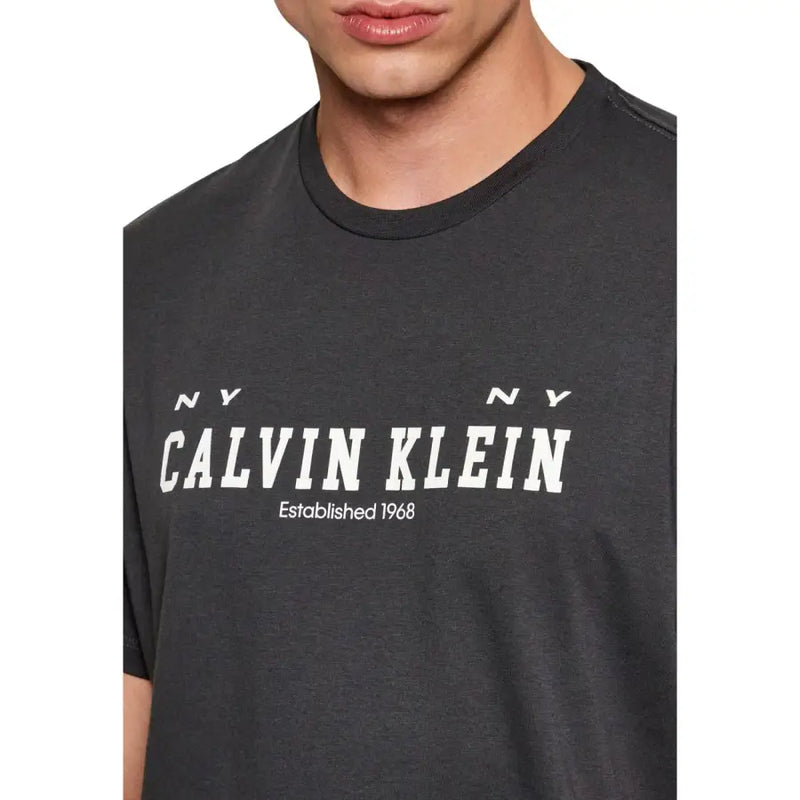 Dunkelgrau Calvin Klein Jeans Männer t-shirt mit einem markanten weißen Logo und dem Aufdruck „NY NY established 1968“ auf der Vorderseite