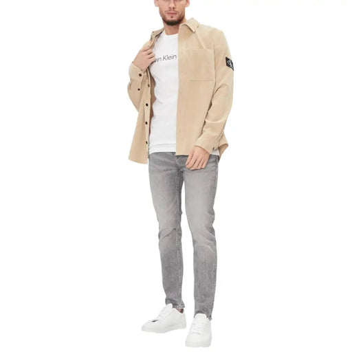 Beige Calvin Klein button-up shirt with chest pocket and black logo patch on sleeve for everyday wear