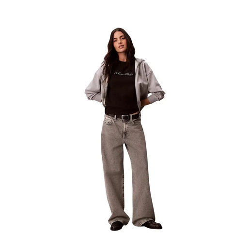 Weit geschnittene graue Jeans mit verwaschenem Look und dezenter Struktur, kombiniert mit einem schwarzen Baumwoll-T-Shirt von Calvin Klein Jeans für Damen mit Rundhalsausschnitt.