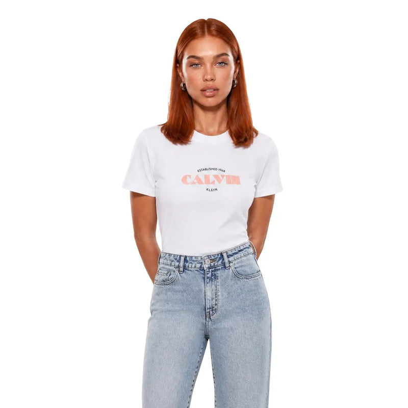 Weißes Calvin Klein Jeans Damen-Baumwoll-Kurzarmshirt mit Pfirsich-Logo und dem Aufdruck „Gründung 1969“ auf der Vorderseite