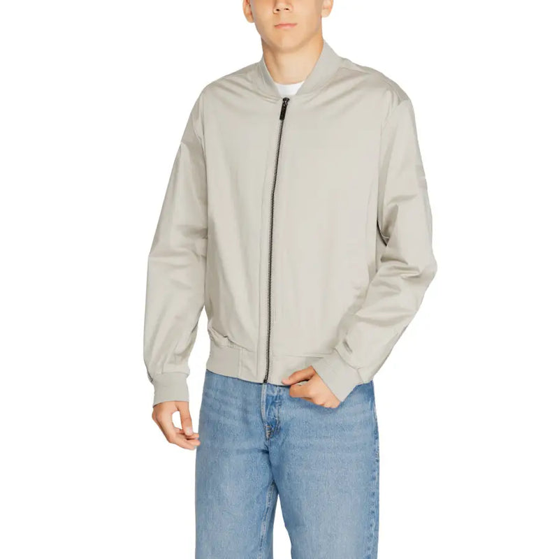 Men’s light grey bomber jacket with black zipper, ribbed details, over white t-shirt and light wash jeans
