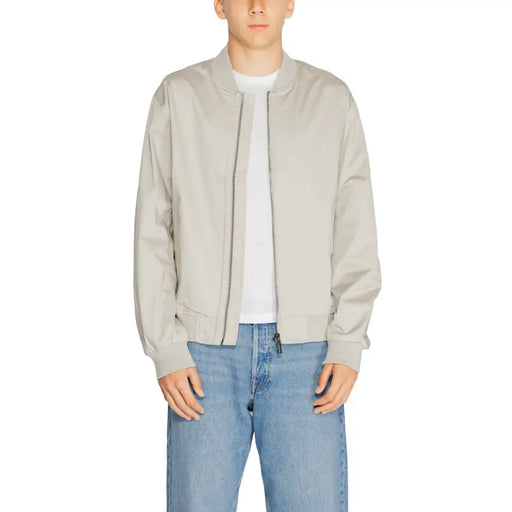 Men’s light grey bomber jacket with white t-shirt and blue jeans displayed in Calvin Klein product