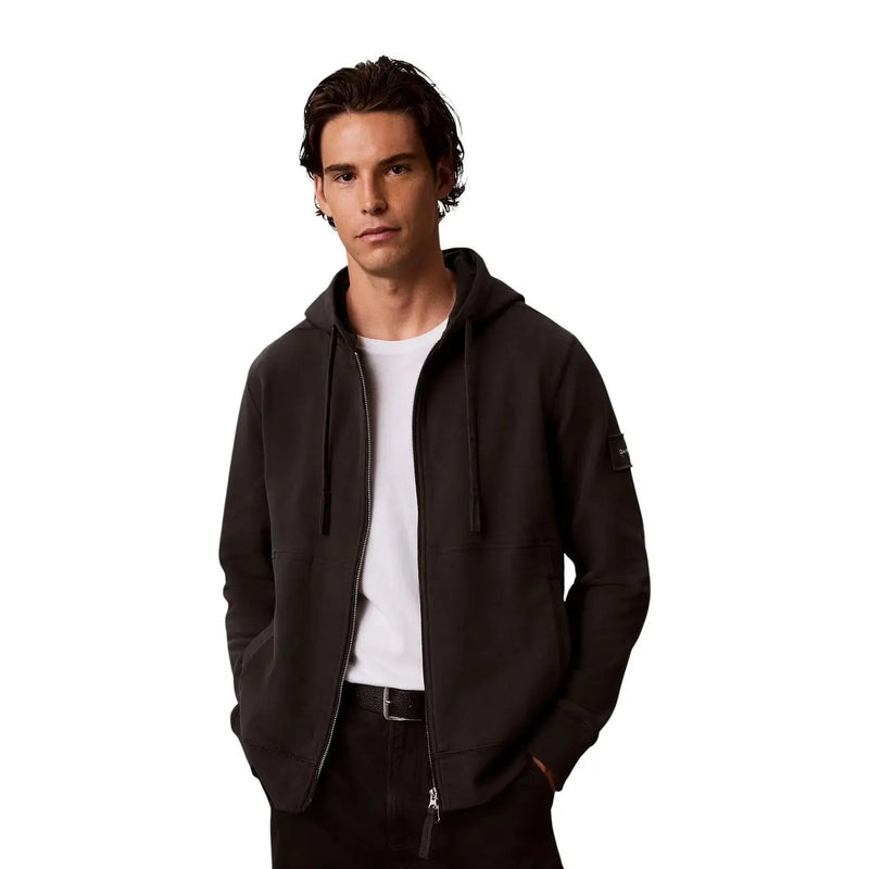 Grauer Herren-Hoodie von Calvin Klein aus Baumwolle mit schwarzer Reißverschluss-Kapuzenjacke, dezent strukturiertem Stoff und Aufnäher am Ärmel.