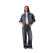 A woman wearing a dark-wash denim jacket with rolled-up sleeves and wide-leg jeans with calvin klein white cotton sweatshirt