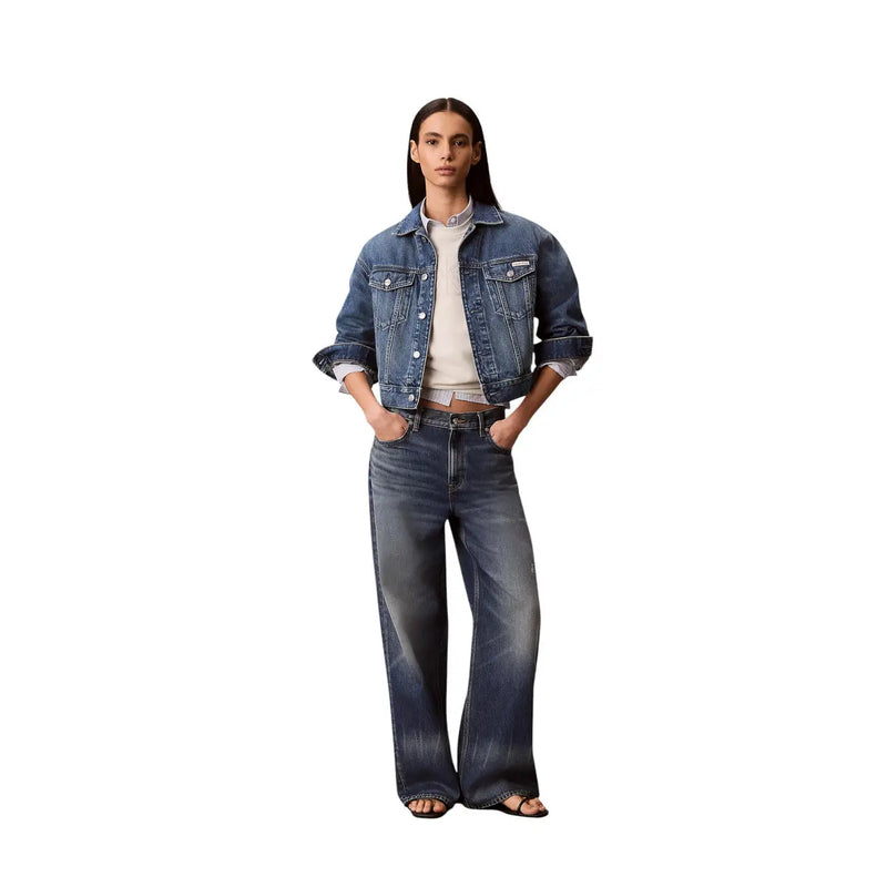 A woman wearing a dark-wash denim jacket with rolled-up sleeves and wide-leg jeans with calvin klein white cotton sweatshirt