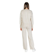 Cremefarbener Strickpullover mit gerippten Bündchen und Saum, kombiniert mit einer passenden, weit geschnittenen Hose in Beige.