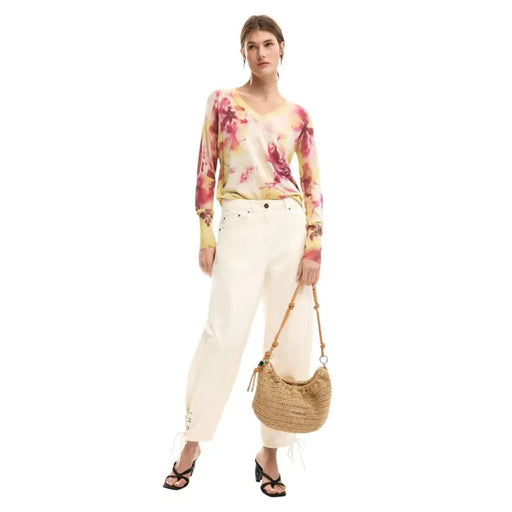 A woven straw handbag with a curved crescent shape and natural tan color featured with desigual pink floral knitwear for women