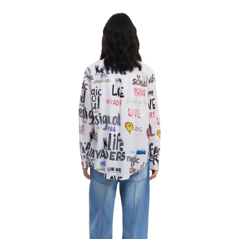 White collared blouse with colorful graffiti-style print paired with light wash blue jeans