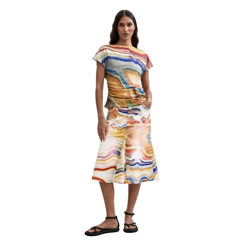 A woman wearing a Desigual women beige round neck polyester T shirt with a vibrant geode-like multicolored pattern
