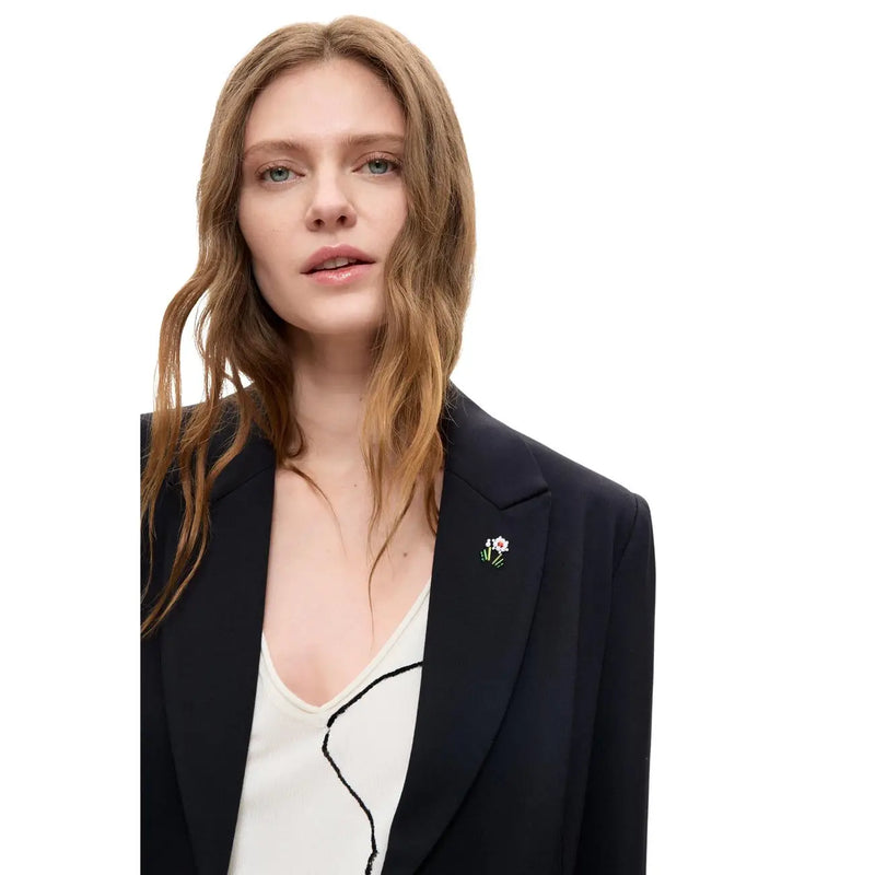 A delicate floral metallic pin with white flower and green stem on a desigual women black blazer viscose blend long lapel