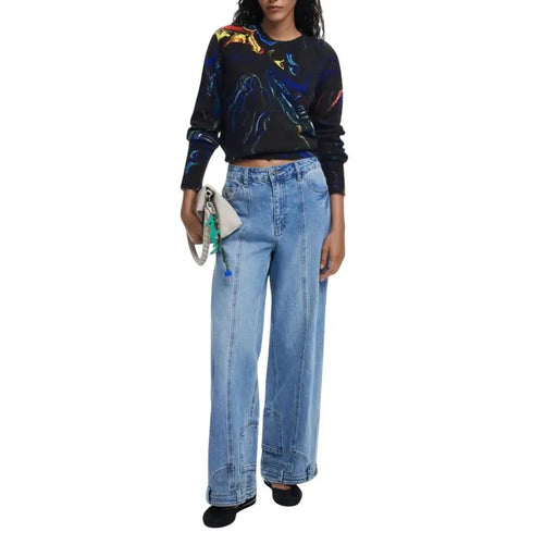 Woman wearing Desigual black long-sleeved abstract patterned knitwear with light blue wide-leg jeans
