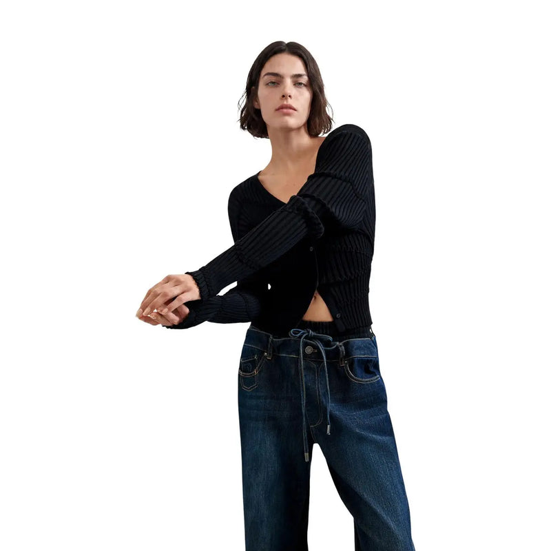 Schwarzer, gerippter Cardigan mit langen Ärmeln und V-Ausschnitt, kombiniert mit einer blauen Desigual Damenjeans aus Baumwollmischgewebe.