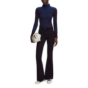 Das Model trägt einen marineblauen, gerippten Rollkragenpullover und eine ausgestellte Hose von Desigual Bordeaux Jeans.