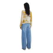 Woman wearing yellow and white long-sleeve top with wide-leg blue jeans from Desigual Fall Winter collection