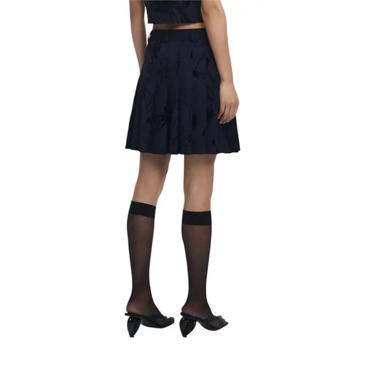 Woman modeling Desigual floral black fall winter skirt with sheer socks and sculptural heels