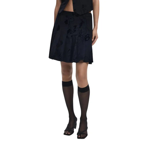 Black knee-length skirt with floral embroidery paired with sheer knee-high socks and open-toed heels