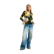 Eine Frau trägt ein schwarzes Strickteil von Desigual aus Acryl-Mischgewebe mit einem schwarz-gelben Blumen-Tie-Dye-Muster.