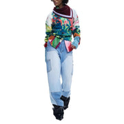 Grüner, langer Strickpullover von Desigual aus Acrylmischung mit farbenfrohem, abstraktem Muster und bordeauxrot-weißem Saum, getragen über einer Patchwork-Jeans.