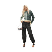 Schwarze Cargohose mit elastischen Bündchen und mehreren Taschen, kombiniert mit einem grünen Strickpullover aus Wollmischung von Desigual für Damen.