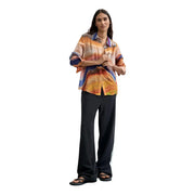 A woman wears a desigual women orange polyester button blouse with vibrant abstract print and flowing sleeves
