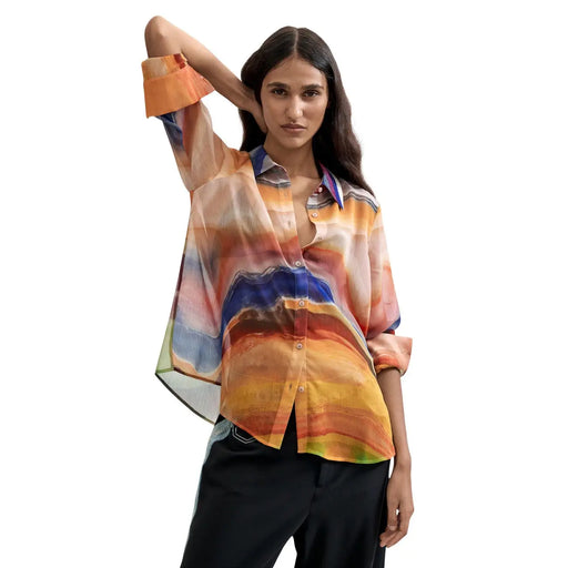 Eine fließende, leicht transparente orangefarbene Polyesterbluse von Desigual für Damen mit einem lebhaften abstrakten Muster in Orange-, Blau- und Gelbtönen.