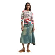 Eine Frau trägt einen roten Desigual-Damenpullover aus Viskosemischgewebe mit buntem Wirbelmuster und einen Jeansrock.