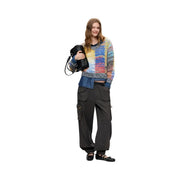 Frau trägt einen roten Desigual-Strickpullover aus Wollmischung mit farbenfrohem Strukturmuster, dazu Jeans und Cargohosen.