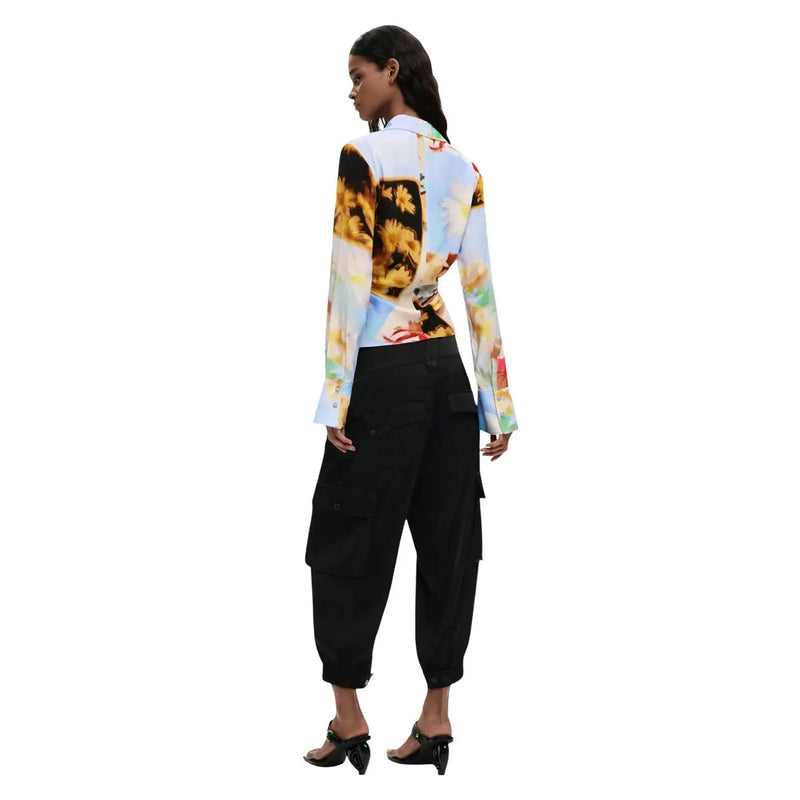 A woman wearing a Desigual women yellow floral viscose long shirt with sunflower print over black cargo pants