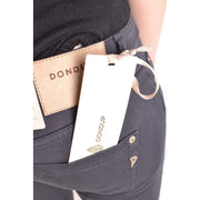Weißes, rechteckiges Markenetikett mit goldener Schrift, befestigt mit beigefarbenem Band an einer grauen Baumwoll-Stretch-Jeans von Dondup für Damen.