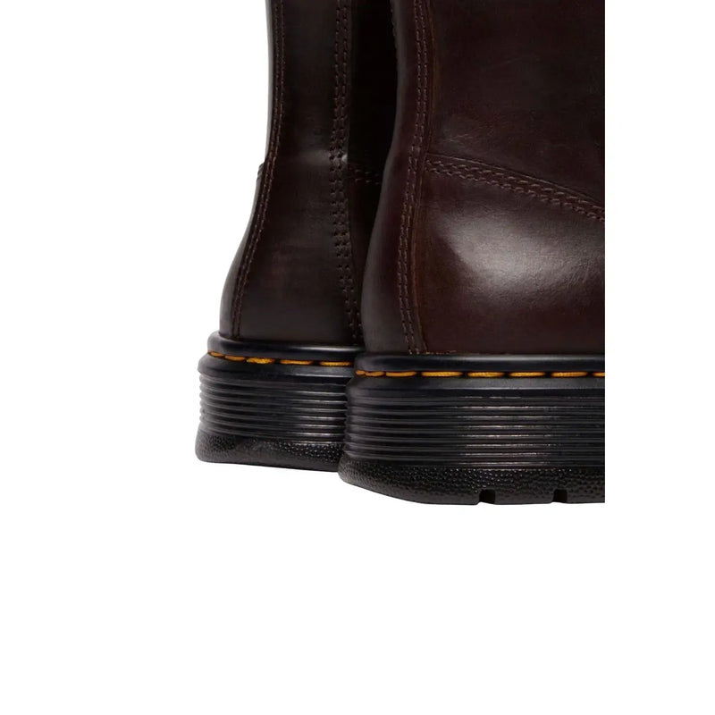 Dunkelbraune Dr. Martens Herren-Chukka-Boots aus Leder mit schwarzen Gummisohlen und gelben Ziernähten am Rahmen.