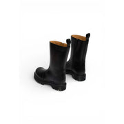 Dr Martens women black leather ankle boots with chunky sole tan lining and zip closure shown from the back side