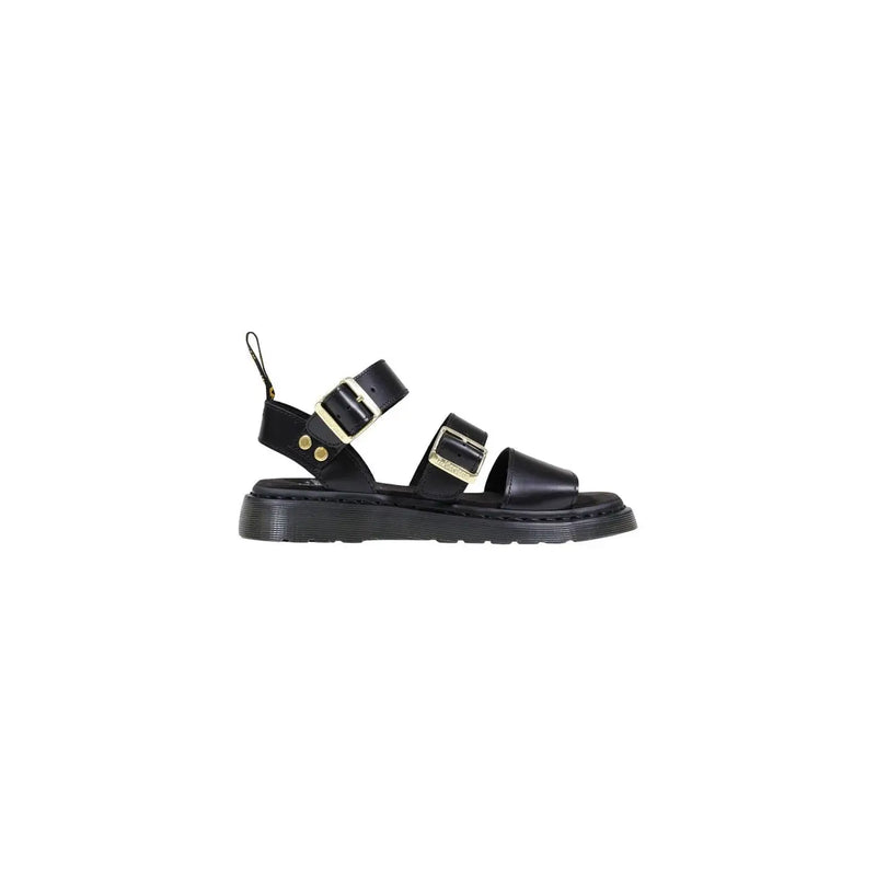 Dr Martens women black leather buckle sandals with gold-tone buckles and chunky rubber sole visible from the back