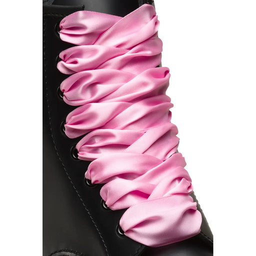 Dr. Martens Damen-Stoffschuhe in Pink mit pinkfarbenen Satinschnürsenkeln, die durch schwarze Ösen an einem Stiefel gefädelt sind.