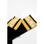 Schwarze Dr. Martens Damen-Stretchunterwäsche aus Baumwollmischgewebe, kombiniert mit schwarz-gelb gestreiften Socken mit weißen Dr. Martens-Buchstaben.