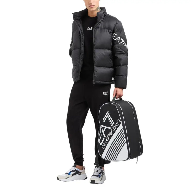 Schwarze und weiße EA7 Emporio Armani Tennistasche mit markanten Diagonalstreifen und Logo-Branding, dazu ein schwarzes EA7 Herren-Sweatshirt aus Baumwolle mit Rundhalsausschnitt.