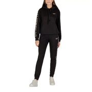 Woman in black tracksuit with white side stripe, featuring front pockets and hood