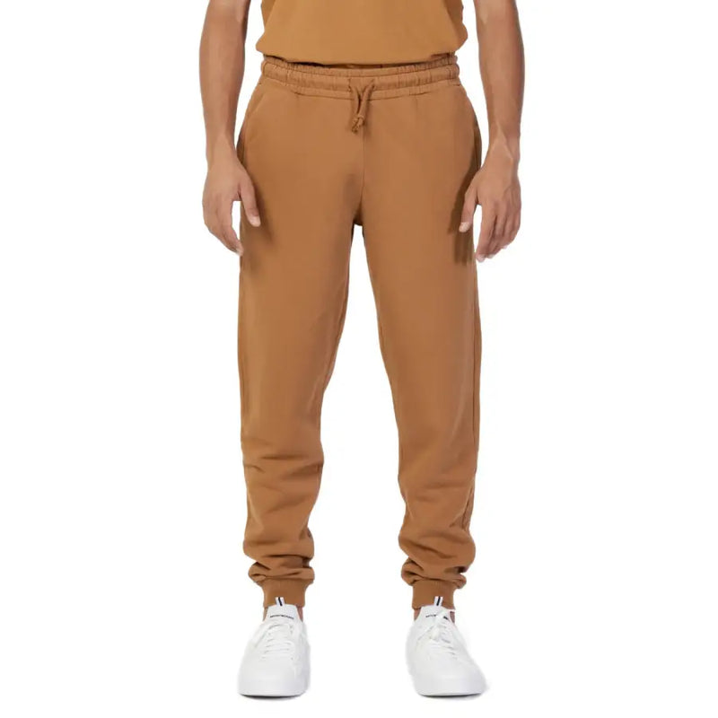 Men’s plain brown cotton sweatpants with drawstring and white athletic shoes for casual wear