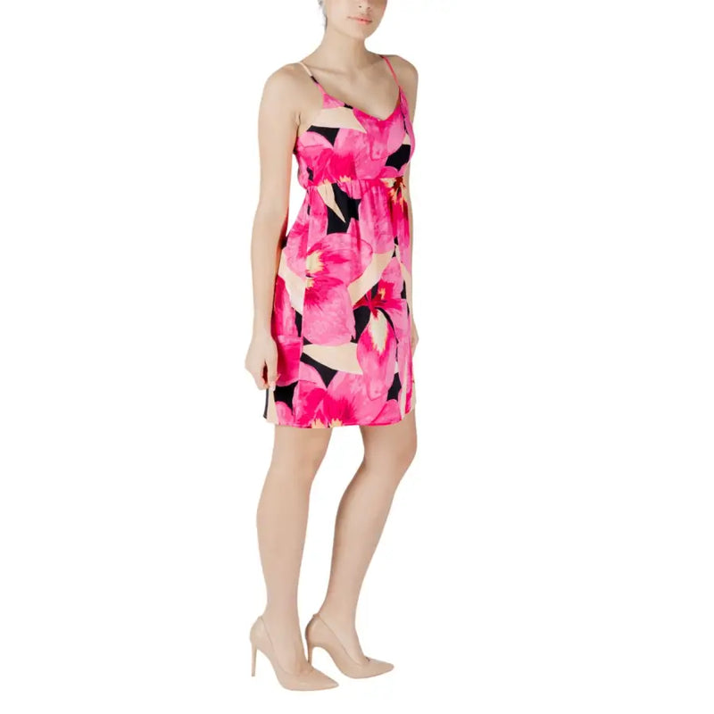 A vibrant fuchsia floral print sleeveless dress with black and cream accents and thin spaghetti straps