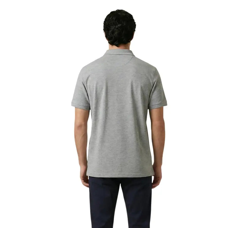 Ein Mann trägt ein graues Gant Herren-Poloshirt aus Stretch-Baumwolle mit kurzen Ärmeln, klassischem Kragen und sauber verarbeiteten Nähten.